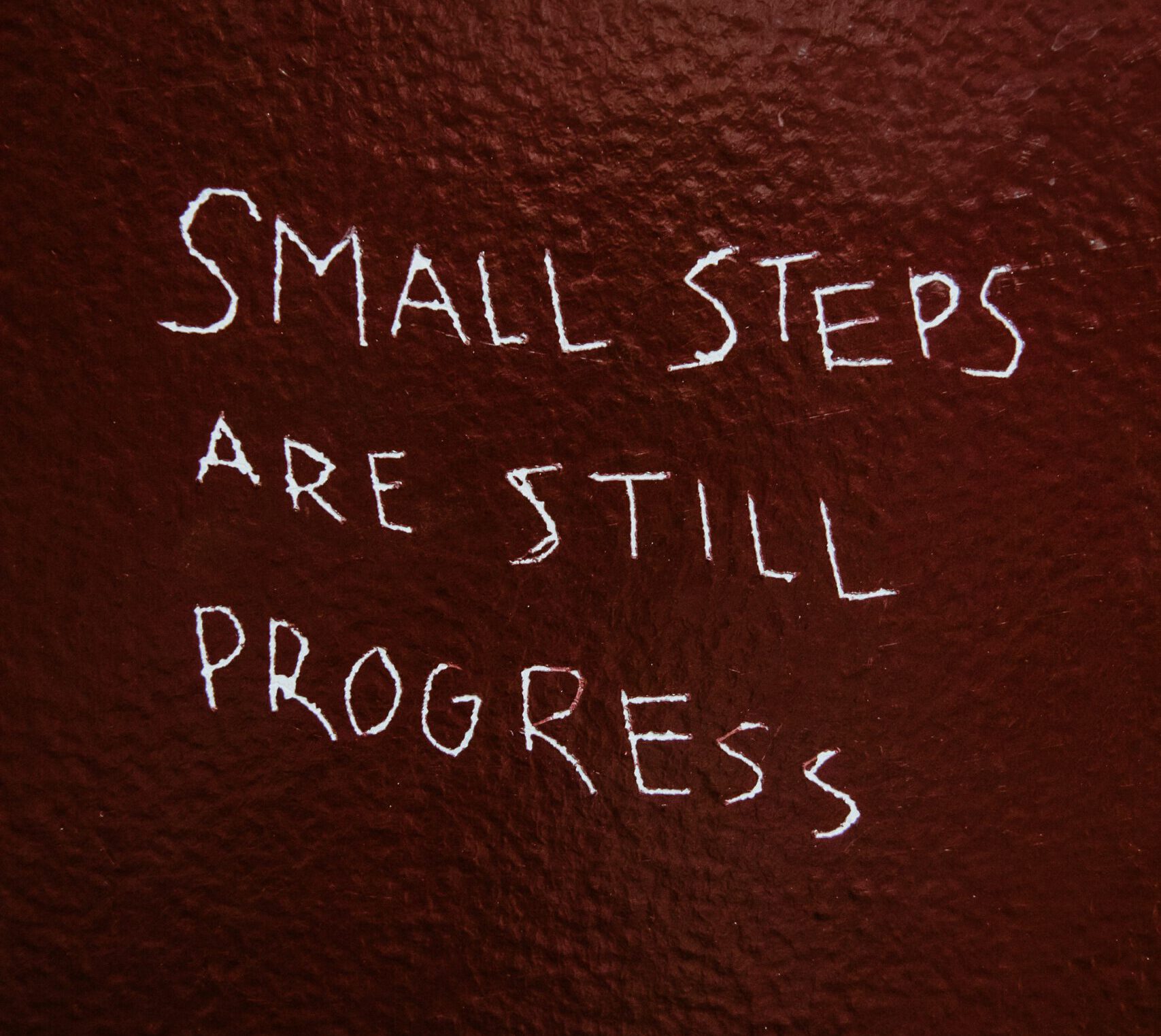 Wand, auf der steht: "Small steps are still progress"